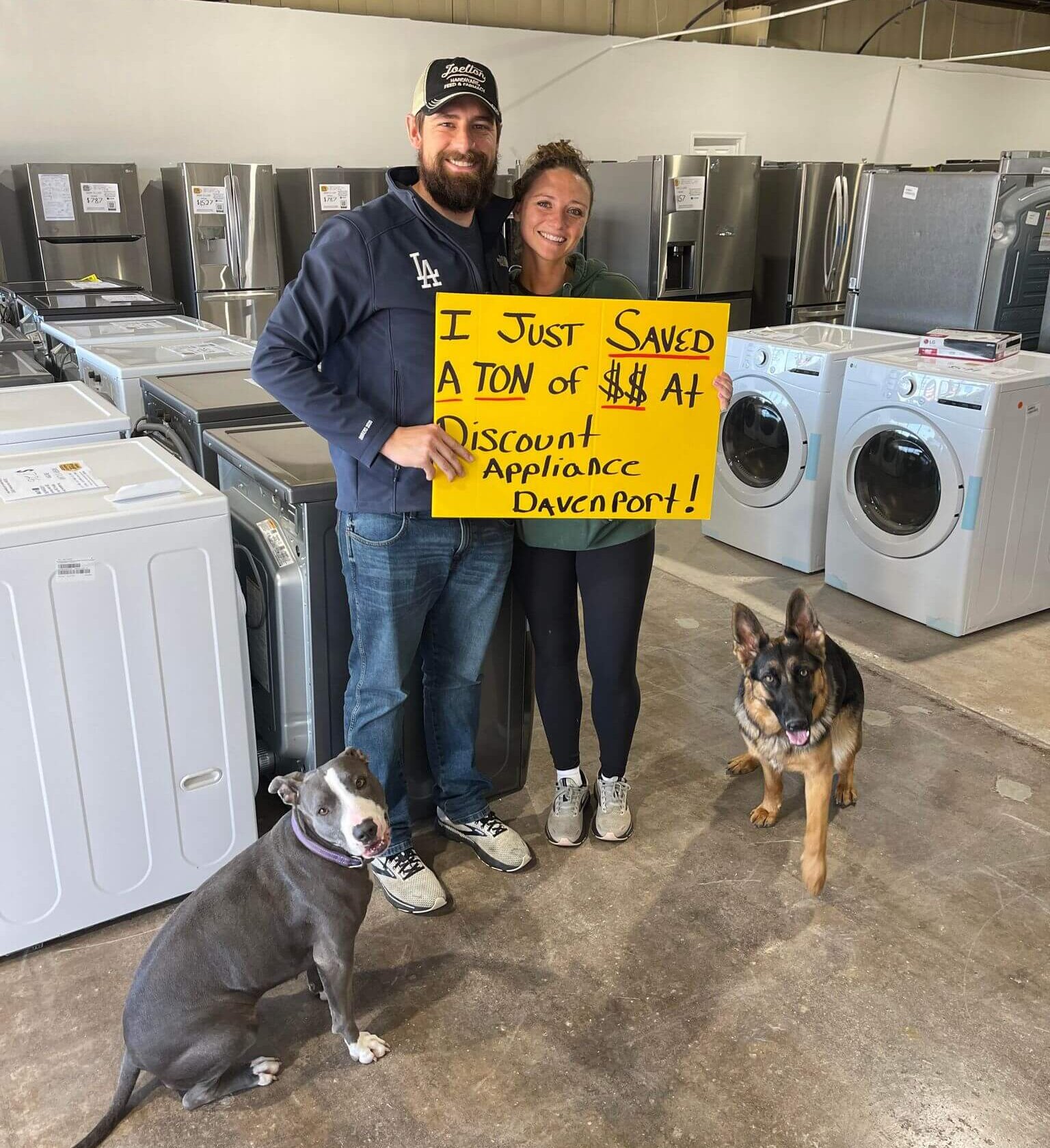A couple with their two dogs holding a sign that says